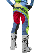 Alpinestars 2024 Techstar Ocuri crossbroek, motorcrossbroek, lichtblauw met fluogeel en bessenrood, achteraanzicht gedragen met witte en zwarte motorcrosslaarzen, voorzien van opvallende kleurvlakken en een groot Alpinestars-logo op het zitvlak