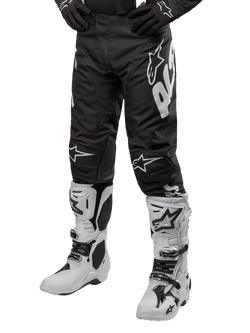 Alpinestars 2024 Racer Hana Pants, pantalon de motocross, noir avec logos blancs, accompagné de gants noirs et de bottes de motocross blanches, équipement de protection technique pour tout-terrain