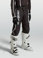 Alpinestars Jeugd Fluid Apex V2 broek, motocrossbroek voor kinderen, zwart en zilver, ergonomische voorgebogen pasvorm.