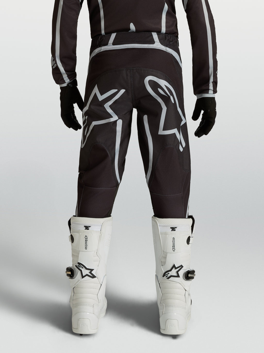 Alpinestars jeugd Fluid Apex V2 broek, zwarte en zilveren motocrossbroek met ergonomische achterzijde en sterlogo's.