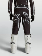 Alpinestars jeugd Fluid Apex V2 broek, zwarte en zilveren motocrossbroek met ergonomische achterzijde en sterlogo's.