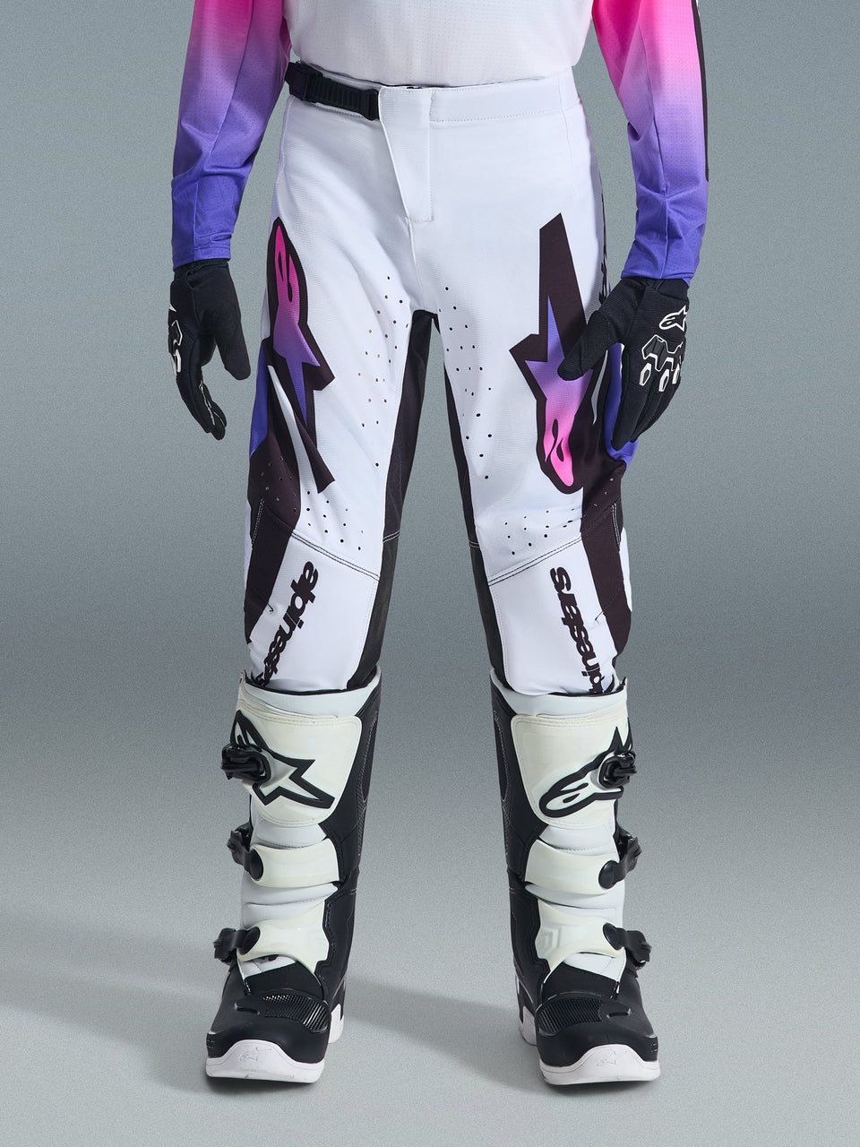 Alpinestars 2026 Youth Supertech Vista Pants, Motocross Pants, White Purple and Black, featuring vibrant gradient star logos and Alpinestars wordmark, worn with matching jersey and white and black boots, athletic race fit for competitive youth racing