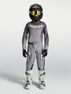 Alpinestars Fluid Amber Junior, pantalon de motocross pour enfant, gris et sable, construction en polyfibre 600D, porté avec un équipement complet