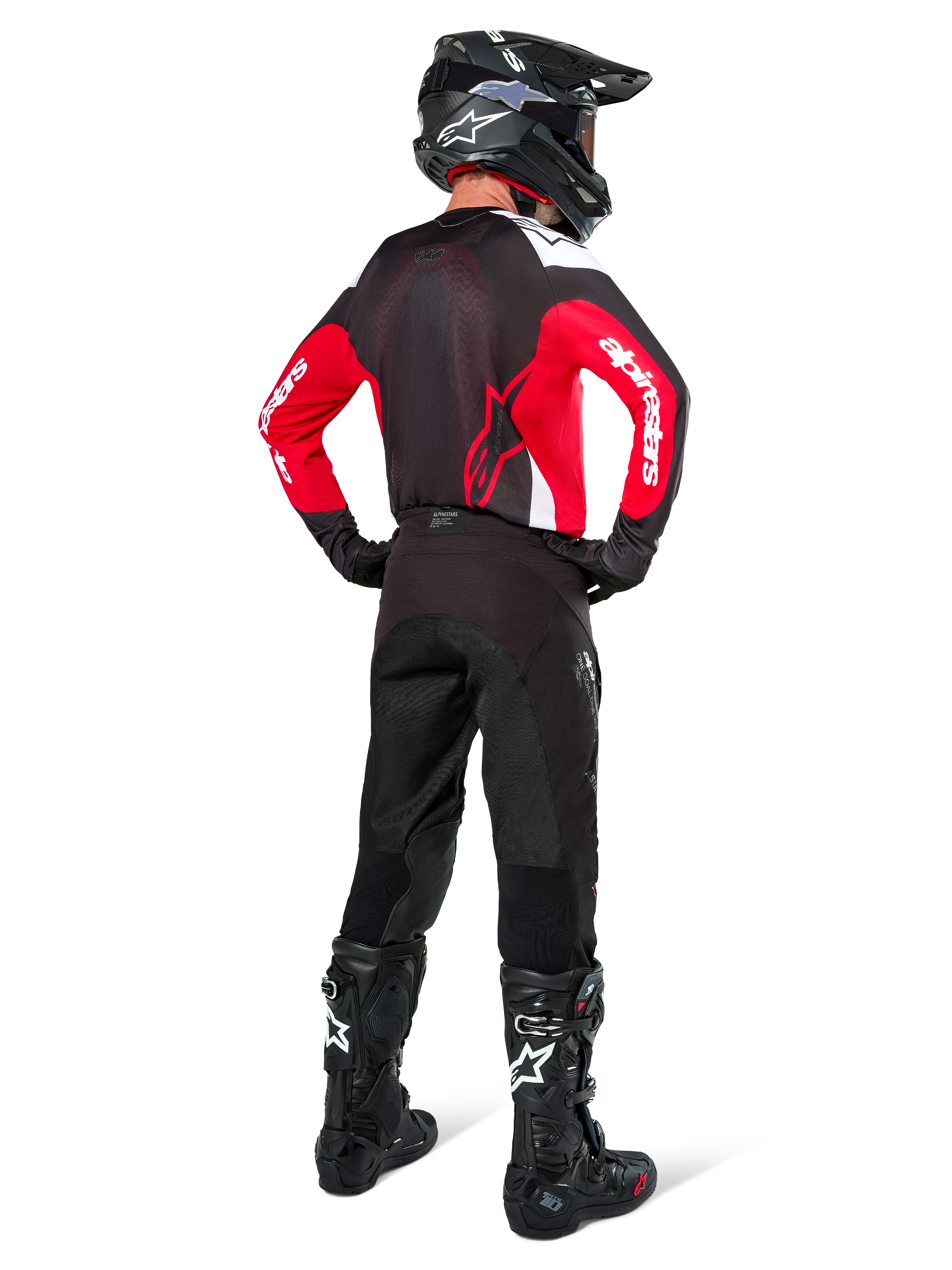 Pilote de motocross vu de dos portant le maillot Alpinestars Pro-Dura noir, rouge vif et blanc, avec pantalon, casque et bottes noirs, montrant le design arrière et les logos sur les manches, équipement de course tout-terrain coordonné