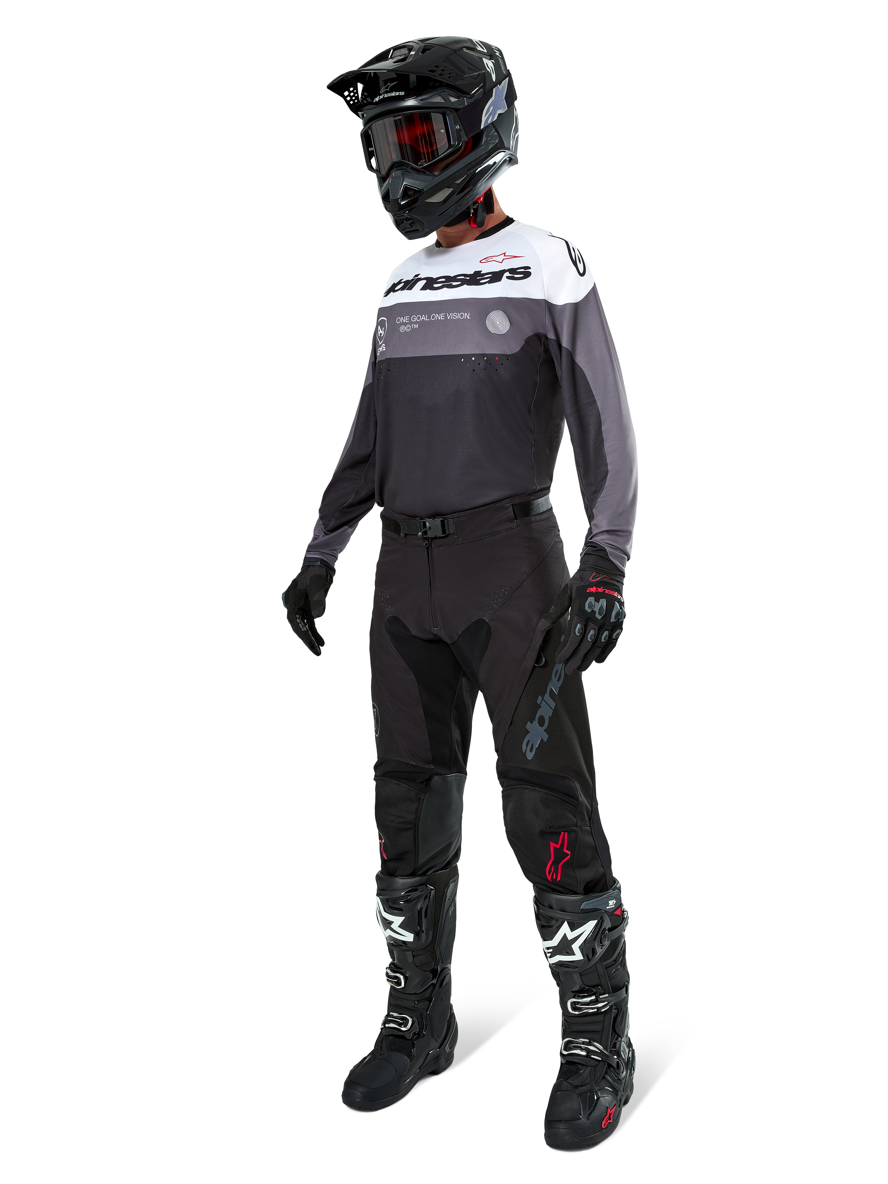 Alpinestars Pro-Dura Trikot in Black Magnet White, Motocross-Fahrer in voller Ausrüstung mit schwarzer Hose, schwarzem Helm mit Brille und schwarz-weißen Stiefeln, technisches Color-Block-Design mit weißen, grauen und schwarzen Paneelen, entwickelt für Enduro- und Offroad-Performance