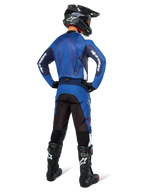 Motocross-Fahrer in der Rückansicht im Alpinestars Pro-Dura Jersey in Navy und Hellblau, dazu passende blau-schwarze Hose, schwarzer Motocross-Helm mit Brille und schwarze Stiefel, zeigt ein koordiniertes Offroad-Rennoutfit
