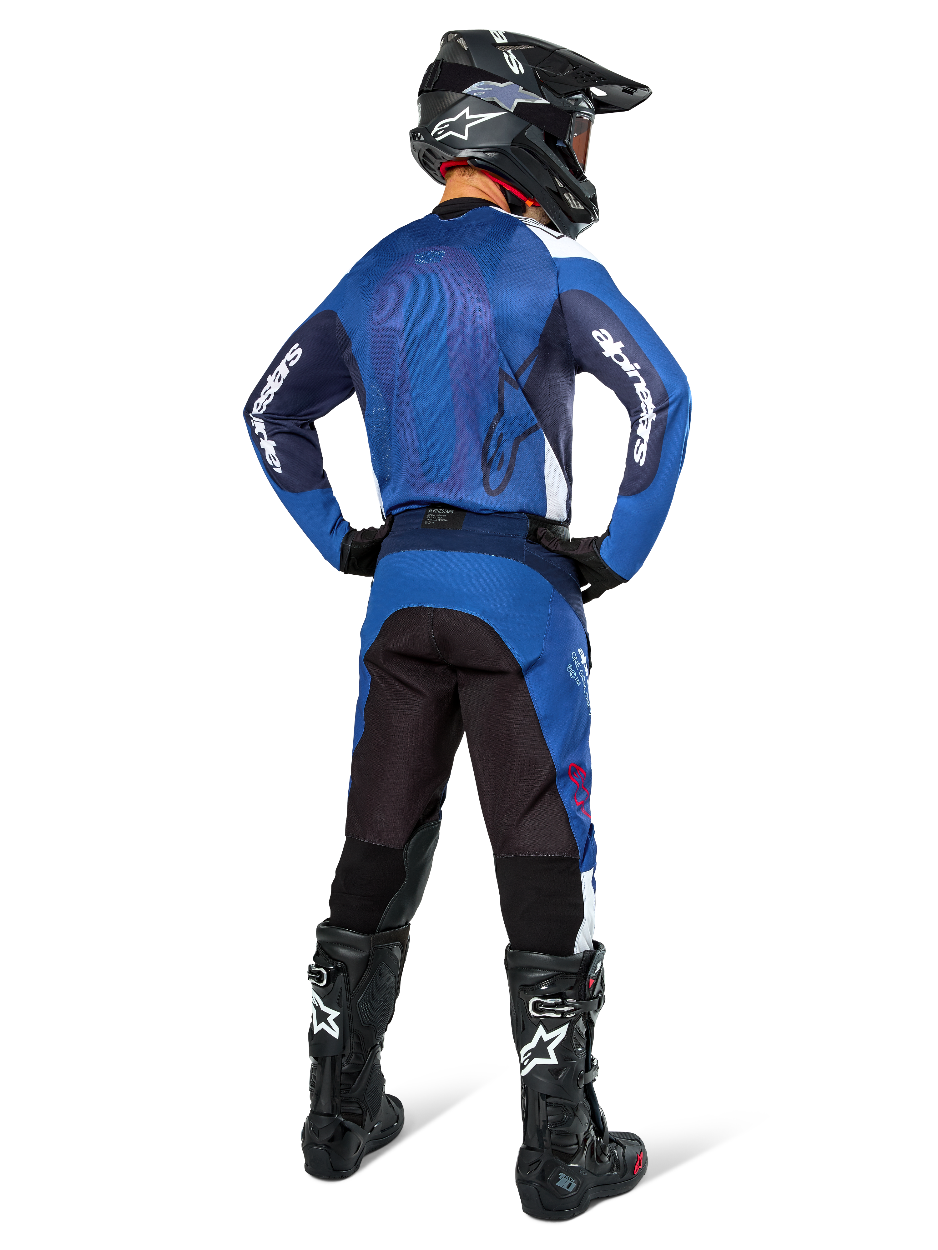 Motocross-Fahrer in der Rückansicht im Alpinestars Pro-Dura Jersey in Navy und Hellblau, dazu passende blau-schwarze Hose, schwarzer Motocross-Helm mit Brille und schwarze Stiefel, zeigt ein koordiniertes Offroad-Rennoutfit