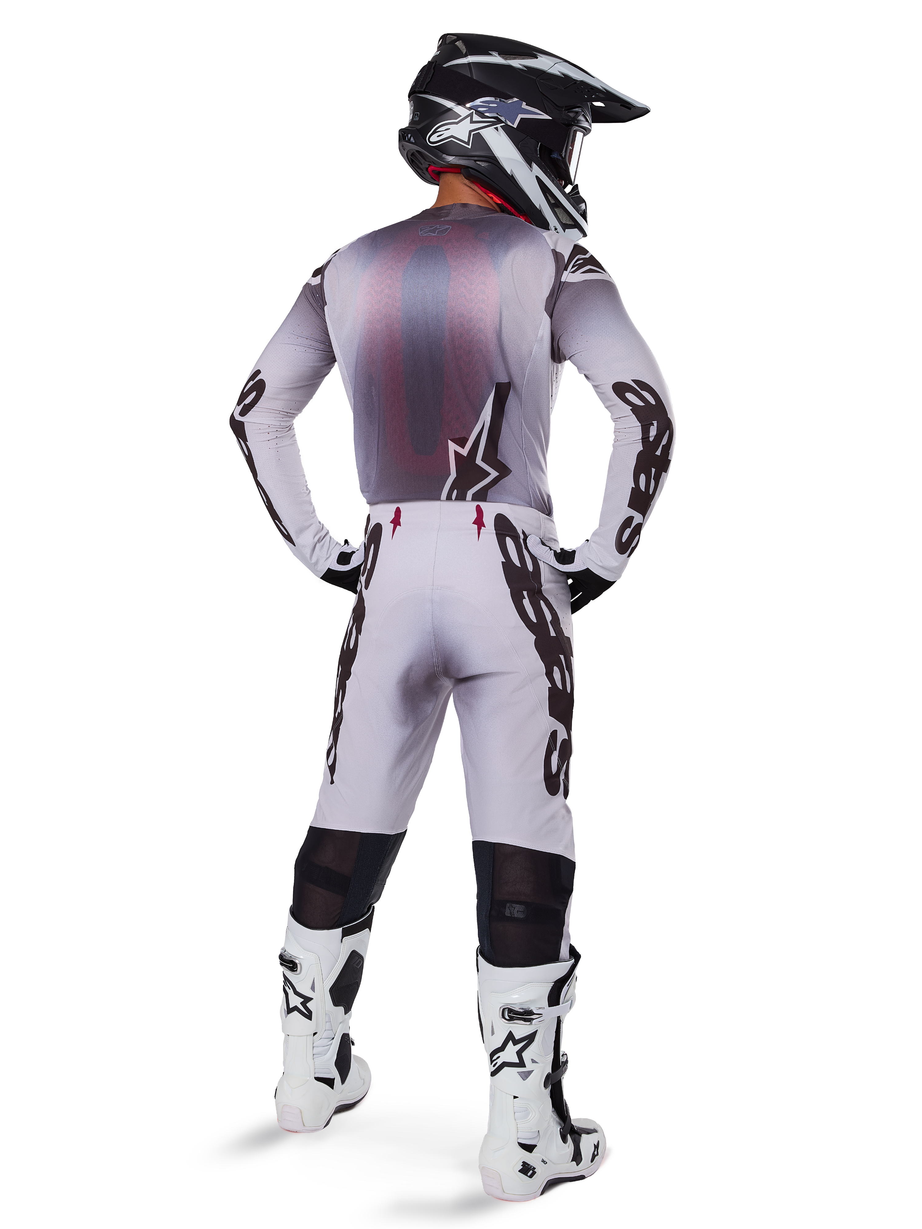 Alpinestars 2025 Supertech Maker Jersey, motorcross jersey, zilver en zwart, achteraanzicht van een rijder met bijpassende uitrusting en witte laarzen, voorzien van opvallende Alpinestars-branding op de mouwen en een sterlogo op de rug, atletische race-pasvorm voor professionele off-road prestaties