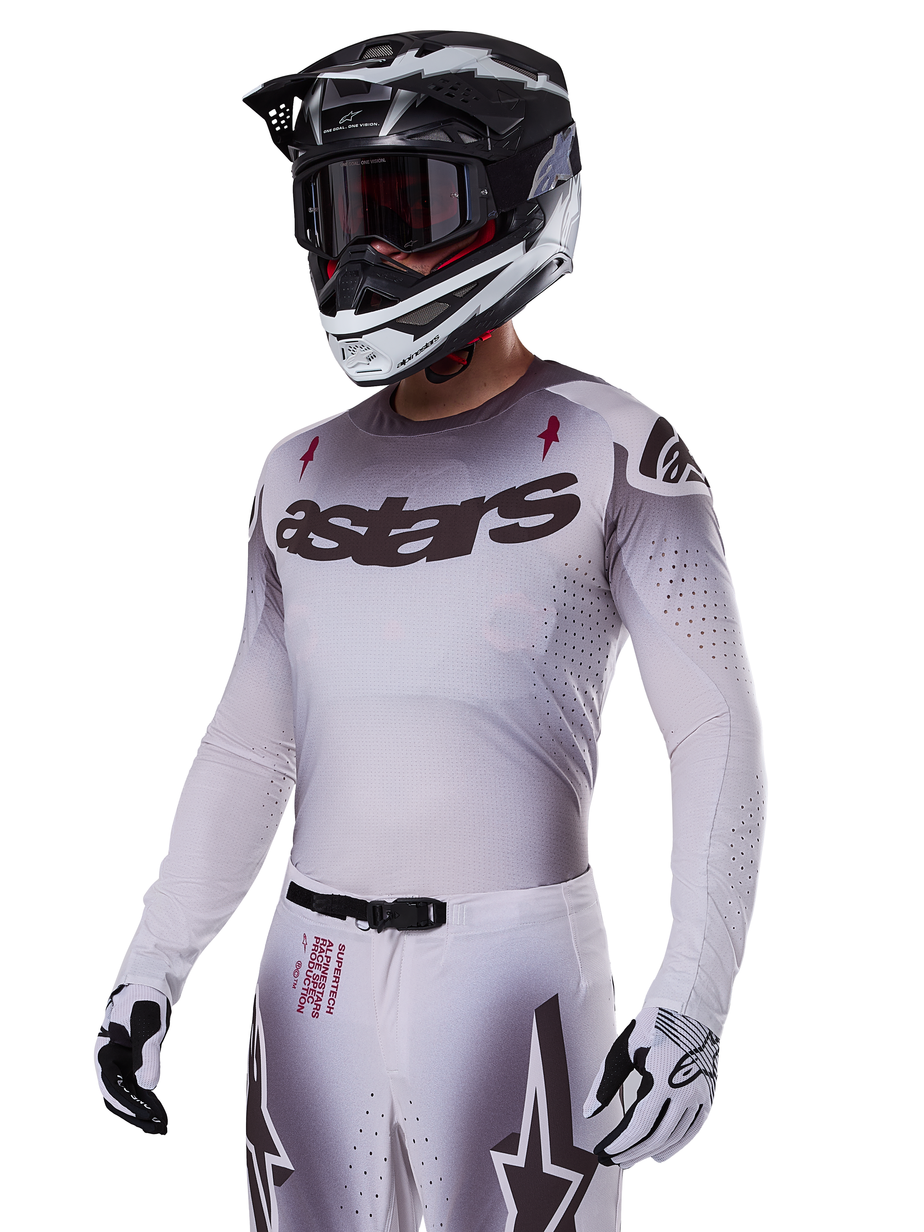 Alpinestars 2025 Supertech Maker Jersey, motorcross raceshirt, zilver en zwart kleurverloop, ademend stretch-mesh met lasergesneden perforaties, gedragen met bijpassende broek en helm, voorzien van 'astars' branding, complete professionele off-road uitrusting