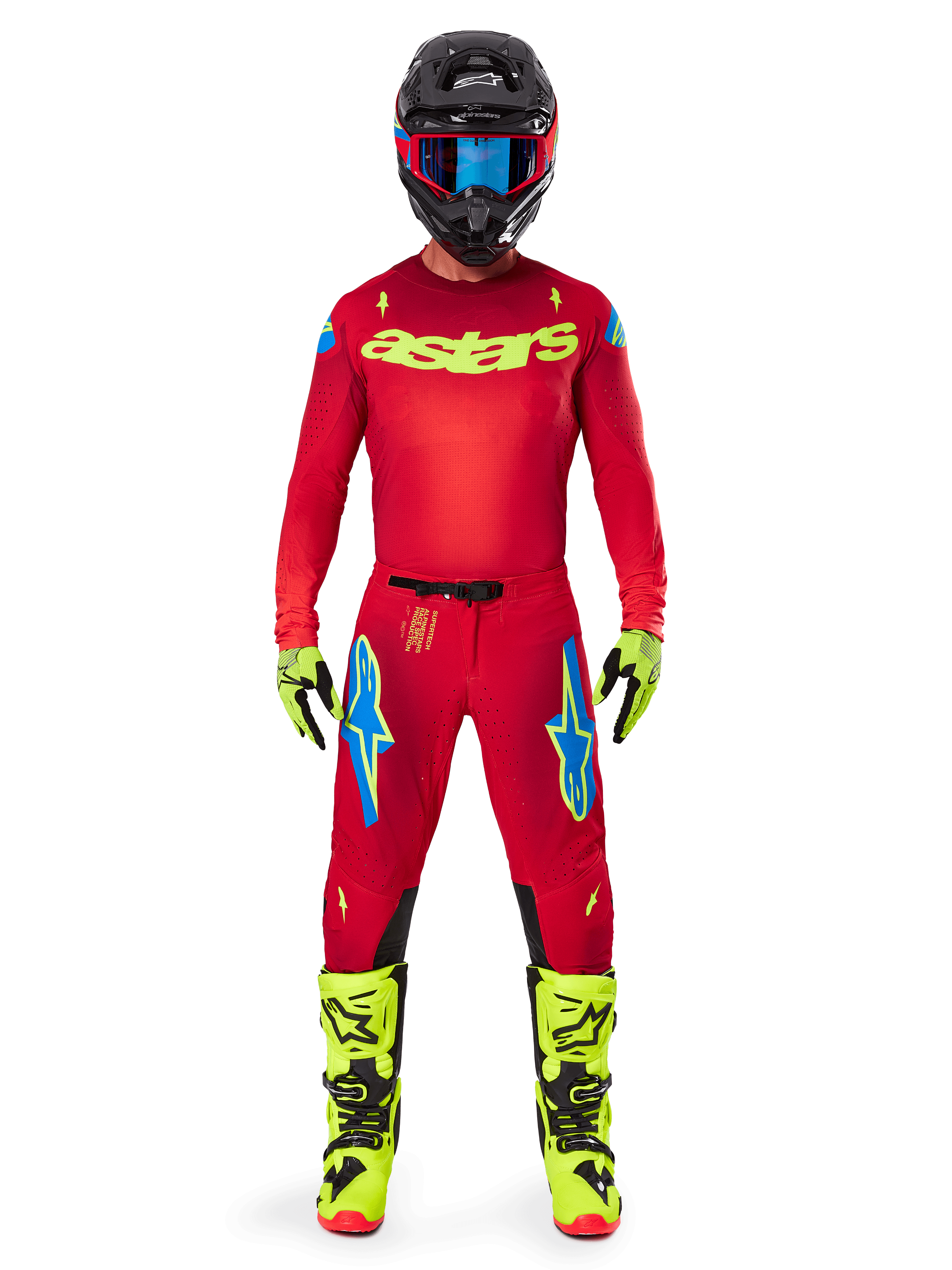 Alpinestars motorcrosser in de 2025 Supertech Maker Jersey en bijpassende broek in felrood en fluogeel, voorzien van een geel 'astars' logo op de borst, zwarte helm met blauwe crossbril, fluogele handschoenen en laarzen, complete professionele race-outfit voor off-road prestaties.
