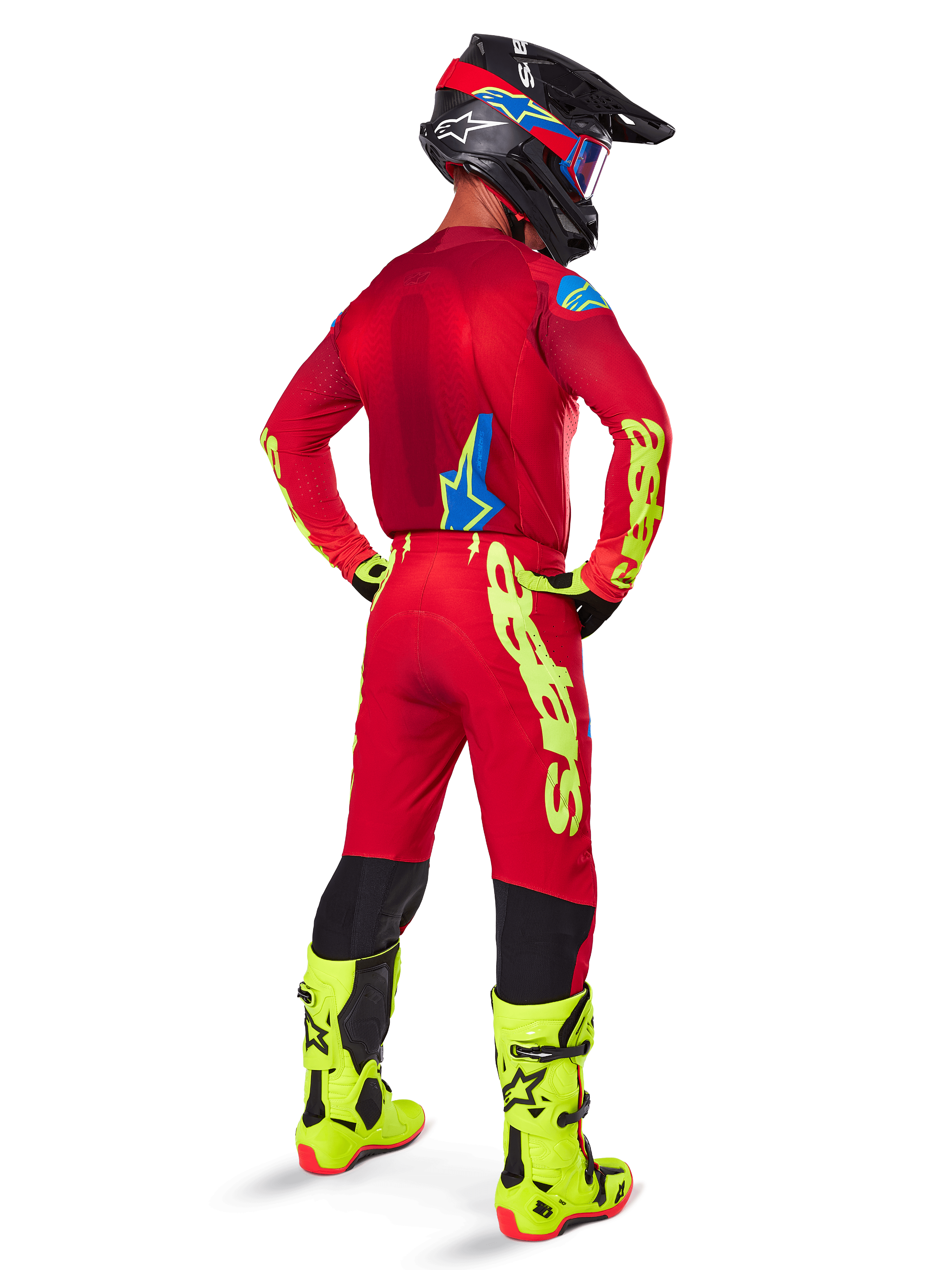 Motorcrossrijder van achteren gezien, draagt de Alpinestars 2025 Supertech Maker Jersey, helderrood en geel fluo, bijpassende broek met gele branding, gele fluo laarzen en een zwart-rode helm, gecoördineerde outfit voor professioneel off-road racen