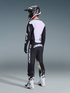 Motocross rider from a rear view wearing the 2026 Racer Air Riway Jersey in Black and White, showcasing the large white mesh back panel for airflow, paired with black pants, black and white helmet, and white racing boots, complete professional gear for off-road performance.