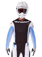 Maillot Alpinestars Techstar Melt 2025, équipement de course de motocross, noir, blanc et bleu, maillot à manches longues avec pantalon et gants assortis, pilote portant une tenue de MX complète avec casque blanc et lunettes