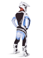 Pilote de motocross portant un équipement de course complet, ensemble Techstar Melt 2025, maillot blanc et bleu clair avec panneau arrière noir, pantalon assorti avec dégradé bleu et accents noirs, casque blanc, bottes blanches et noires, tenue coordonnée pour la course tout-terrain