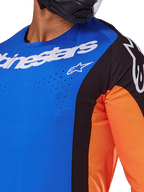 Alpinestars 2025 Techstar Melt Jersey, motorcross shirt, blauw en oranje met zwarte panelen, voorzien van witte Alpinestars-branding en zichtbare lasergesneden perforaties op de borst, gedragen door een rijder met een zwarte helm