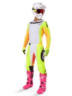 Motocross-Fahrer in kompletter Rennausrüstung, Alpinestars 2025 Techstar Melt Trikot, weiße Vorderseite mit gelben Seiteneinsätzen und orangefarbenen Ärmeln, passend dazu gelbe und weiße Hose, weißer Helm mit roter Brille und leuchtend rosa Stiefel, professionelle Offroad-Rennausrüstung.