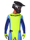 Maillot Alpinestars Techstar Melt 2025, maillot de motocross, jaune fluo et bleu, avec ventilation découpée au laser et coupe sportive de compétition, porté par un pilote avec un casque noir et des gants jaune fluo