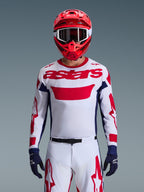 Alpinestars 2026 Racer Riway Trikot in Weiß-Blau-Rot, Motocross-Fahrer mit großem rotem „astars“-Logo auf der Brust, dunkelblaue Seiteneinsätze, passende weiß-rote Motocross-Hose, roter Helm mit weißer Brille, dunkelblaue Handschuhe, komplette Offroad-Rennausrüstung