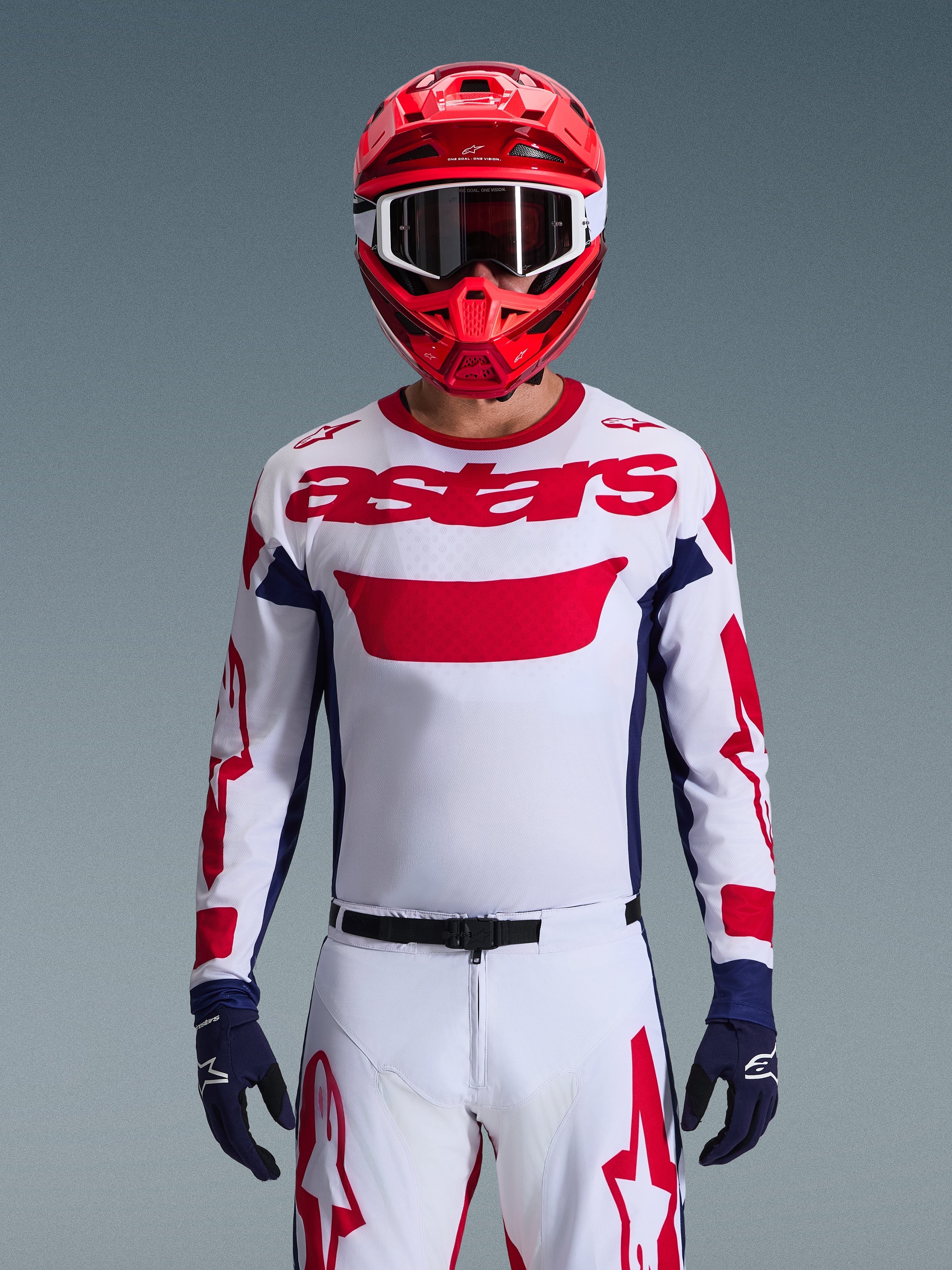 Alpinestars 2026 Racer Riway Trikot in Weiß-Blau-Rot, Motocross-Fahrer mit großem rotem „astars“-Logo auf der Brust, dunkelblaue Seiteneinsätze, passende weiß-rote Motocross-Hose, roter Helm mit weißer Brille, dunkelblaue Handschuhe, komplette Offroad-Rennausrüstung