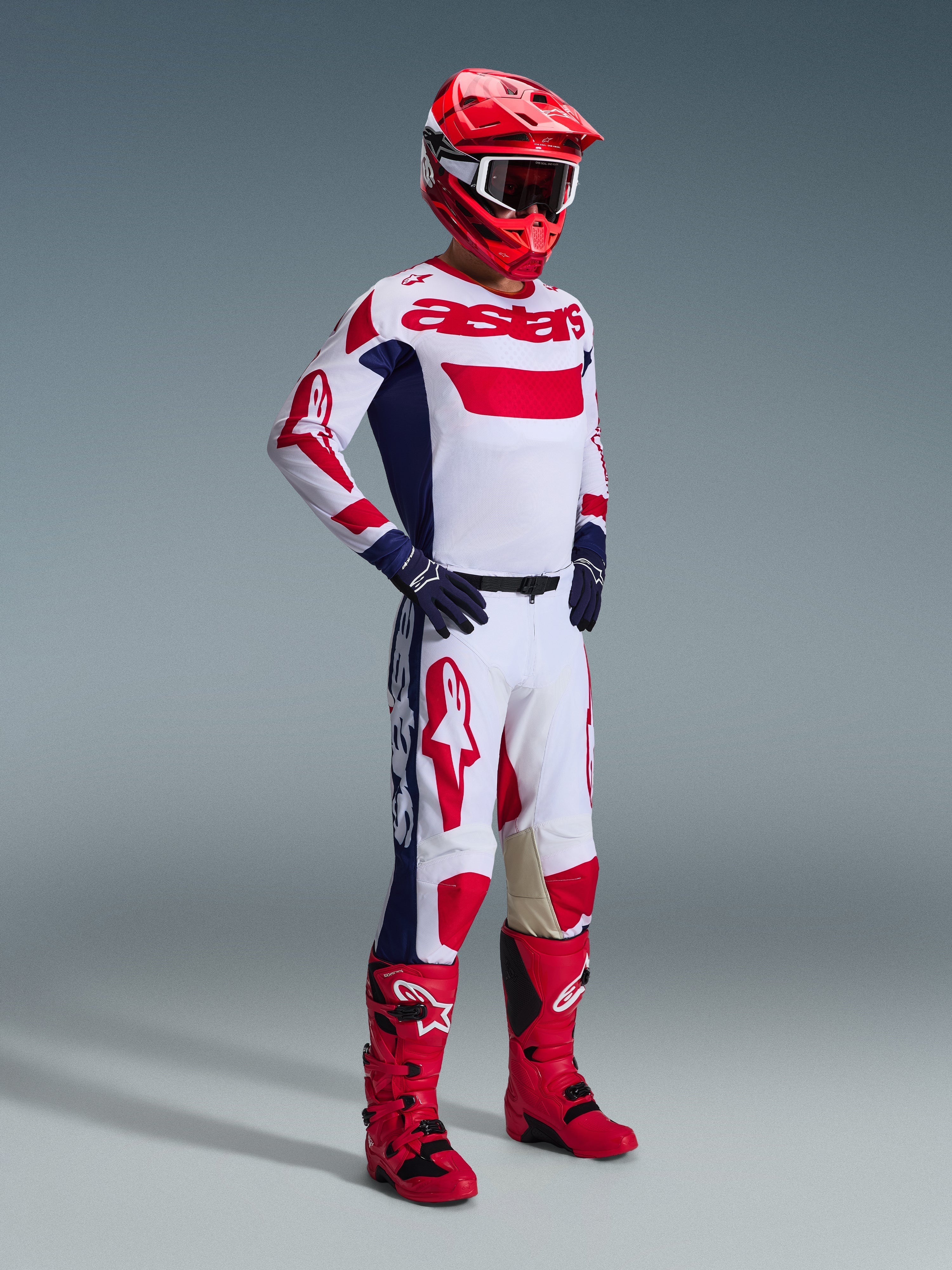 Motocross-Fahrer im 2026 Racer Riway Trikot in Weiß Blau Rot, passende weiß-rote Hose, roter Helm mit weißer Brille, marineblaue Handschuhe und rote Motocross-Stiefel, komplettes Rennbekleidungsset für Offroad-Performance.