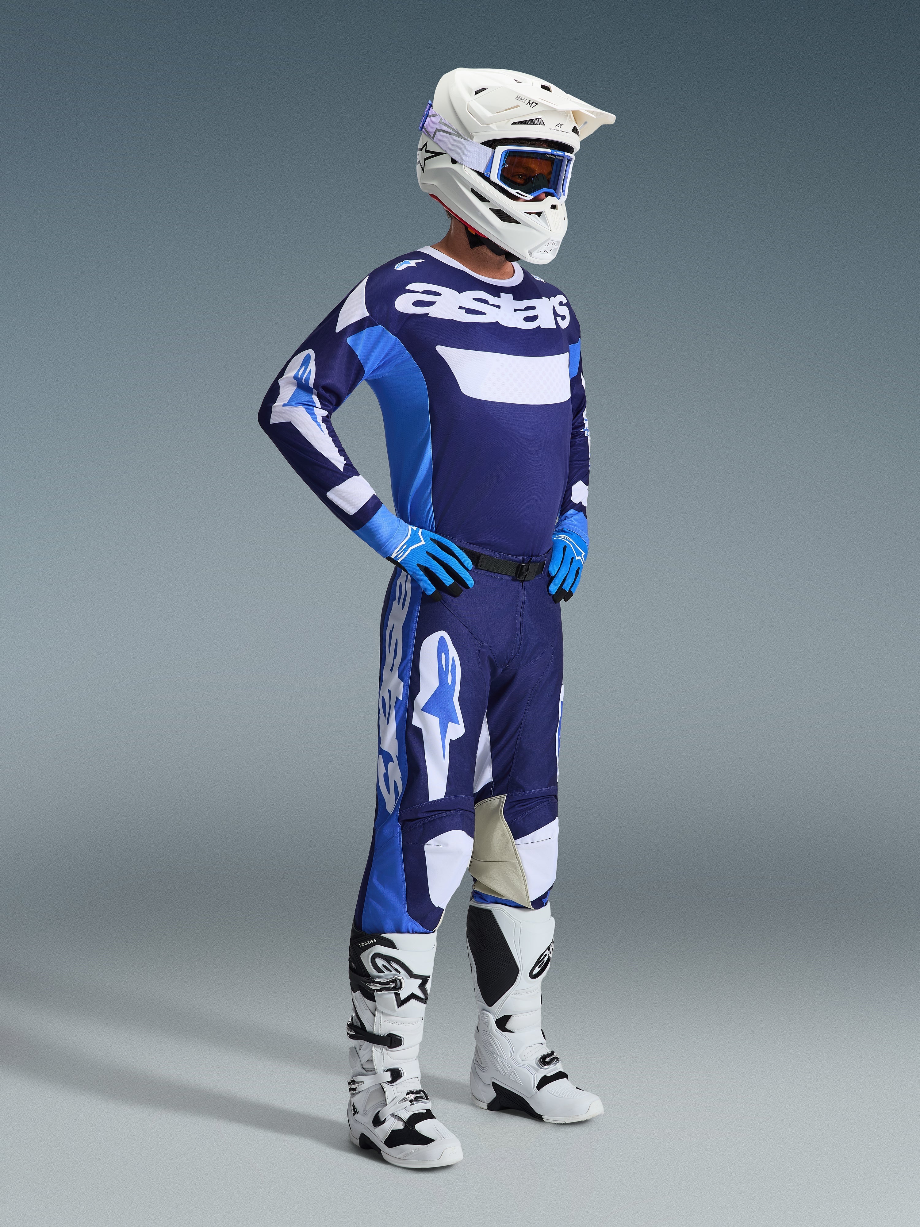 Alpinestars 2026 Racer Riway Trikot in UCLA Blue und Weiß, getragen von einem Motocross-Fahrer mit passender Hose, weißem Helm, blauen Handschuhen und weißen Stiefeln, markantes „astars“-Branding auf der Brust, komplette Offroad-Rennausrüstung