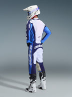 Motocross rider wearing the 2026 Racer Riway Jersey in Ucla Blue and White, paired with matching blue and white motocross pants, a white helmet, and white boots, shown from a back three-quarter view for a complete off-road racing look.