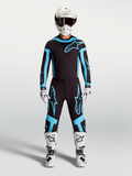 Alpinestars ensemble Supertech Vesta et maillot, tenue de motocross pour homme, noir et turquoise avec bottes et casque blancs, équipement de course tout-terrain.