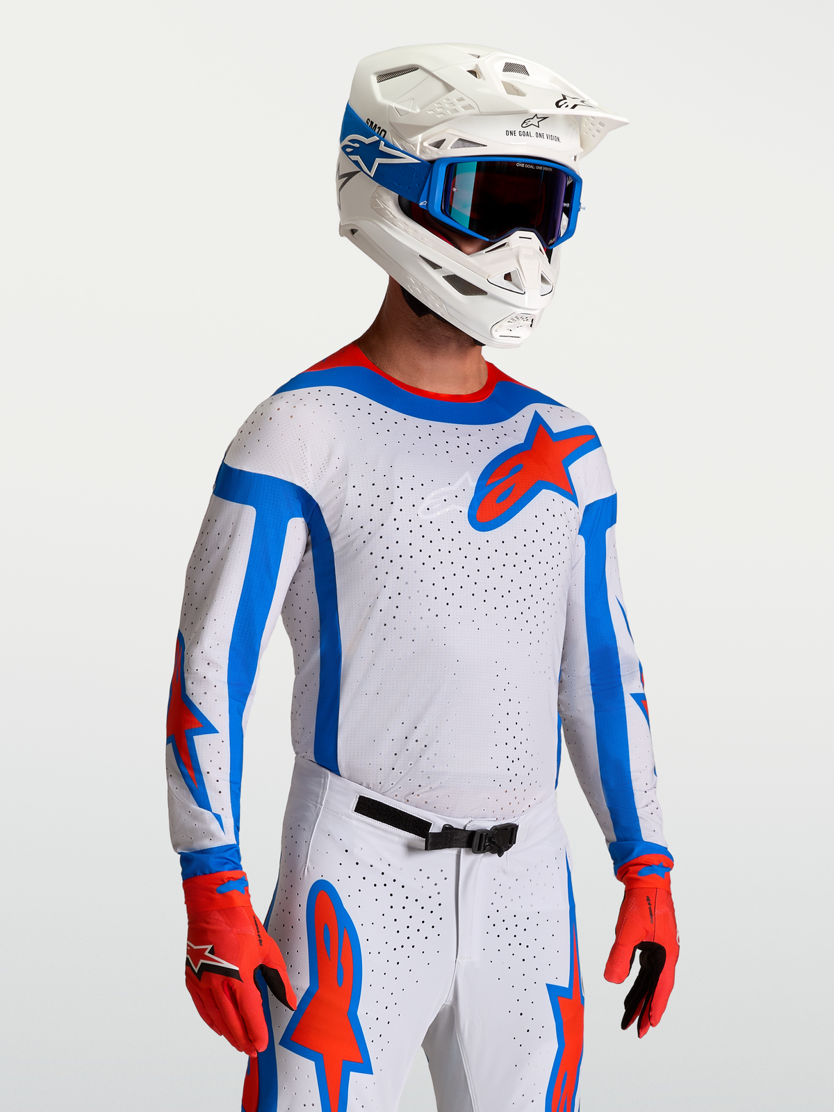 Alpinestars Supertech Vesta Trikot, professionelles Motocross-Renntrikot in Weiß, Rot und Blau, athletische Passform aus atmungsaktivem Stretch-Mesh, getragen von einem Model mit Helm und Handschuhen.