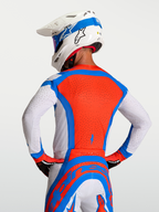 Alpinestars Supertech Vesta Jersey, heren-motocrossjersey in rood, blauw en wit met ademende laser-gesneden perforaties, achteraanzicht van een rijder.