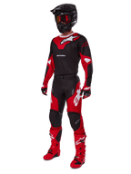Motorcrosser in een volledige race-uitrusting met de Alpinestars 2025 Racer Veil Jersey in zwart en felrood, bijpassende broek, rode laarzen, zwarte helm met rode bril en rood-zwarte handschoenen, gecoördineerde performance-look voor off-road racen