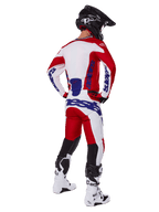 Alpinestars 2025 Racer Veil Jersey en broek, motorcross outfit van achteren gezien, rood en wit met blauwe merkdetails, zwarte helm en witte laarzen, complete kledingset voor off-road racen