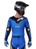 Alpinestars 2025 Racer Veil Jersey, motorcross jersey, blauw en zwart, gedragen met bijpassende motorcrossuitrusting inclusief helm en handschoenen, sportief design met witte Alpinestars branding