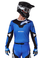 Alpinestars 2025 Racer Veil Jersey, motorcross jersey, blauw en zwart, gedragen met bijpassende motorcrossuitrusting inclusief helm en handschoenen, sportief design met witte Alpinestars branding