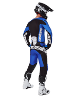 Motorcrosser in volledige race-uitrusting van achteren gezien, 2025 Racer Veil Jersey en bijpassende broek in blauw en zwart, met witte Alpinestars-branding, zwarte helm, wit-zwarte laarzen, gecoördineerde outfit voor off-road racen
