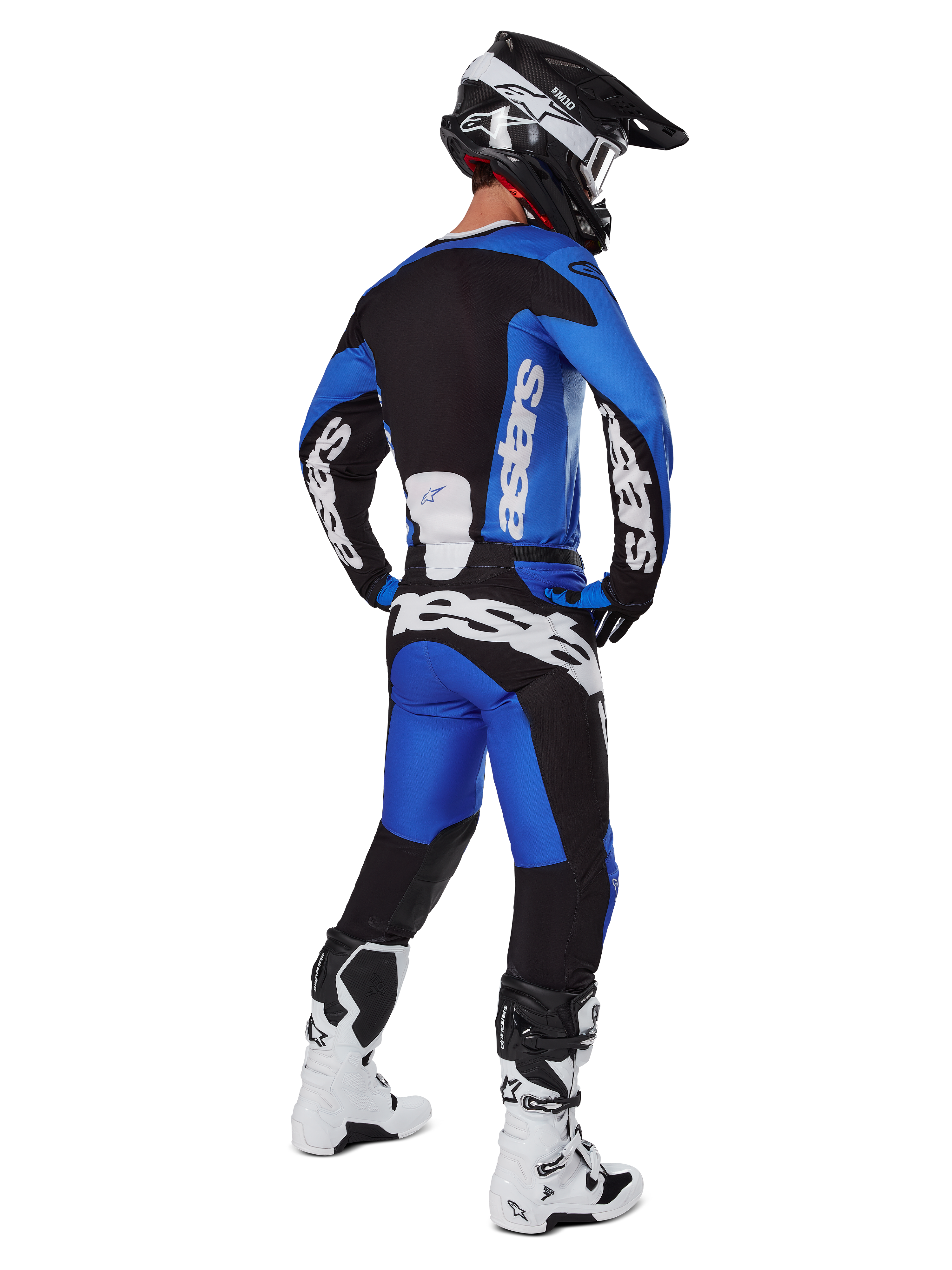 Motorcrosser in volledige race-uitrusting van achteren gezien, 2025 Racer Veil Jersey en bijpassende broek in blauw en zwart, met witte Alpinestars-branding, zwarte helm, wit-zwarte laarzen, gecoördineerde outfit voor off-road racen