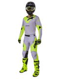 Ensemble d'équipement Alpinestars Racer Veil 2025, tenue de motocross complète, gris et jaune fluo, comprenant maillot, pantalon, casque, lunettes, gants et bottes avec accents noirs, équipement de course professionnel pour performance tout-terrain