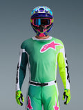 Alpinestars 2026 Racer Portl Jersey, motorcross shirt, groen, wit en zwart met een groot roze Alpinestars-logo op de borst, gedragen door een rijder met een levendige meerkleurige helm en bijpassende bril, professionele off-road racekleding