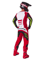Motocross-Fahrer von hinten im Alpinestars 2025 Fluid Haul Gear Set, Hellrot und Schwarz mit weißen Einsätzen, neongelbes Branding auf Ärmeln und Hose, passende rote Stiefel und schwarzer Helm, komplette professionelle Offroad-Rennausrüstung