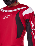 Alpinestars 2025 Fluid Haul Trikot, leuchtendes Rot und Schwarz, Nahaufnahme der Brust und des Arms mit weißem Alpinestars-Branding und Logo, sportliches ergonomisches Design mit geschwungenen Akzenten für Motocross-Performance.