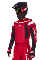 Pilote de motocross portant l'ensemble d'équipement Alpinestars 2025 Fluid Haul rouge, comprenant un maillot rouge avec des accents blancs et noirs, un pantalon rouge assorti avec des graphismes blancs, un casque noir avec logo blanc, des lunettes rouges et jaunes et des gants rouges et noirs, tenue de course de motocross coordonnée