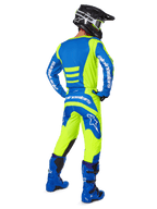 Motocrossrijder van achteren gezien die de Alpinestars 2025 Fluid Haul Gear Set in Yellow Fluo en Blue draagt, met een blauwe jersey met gele accenten, een gele broek met blauwe panelen op het zitvlak en de knieën, gecombineerd met felblauwe laarzen en een zwarte helm.