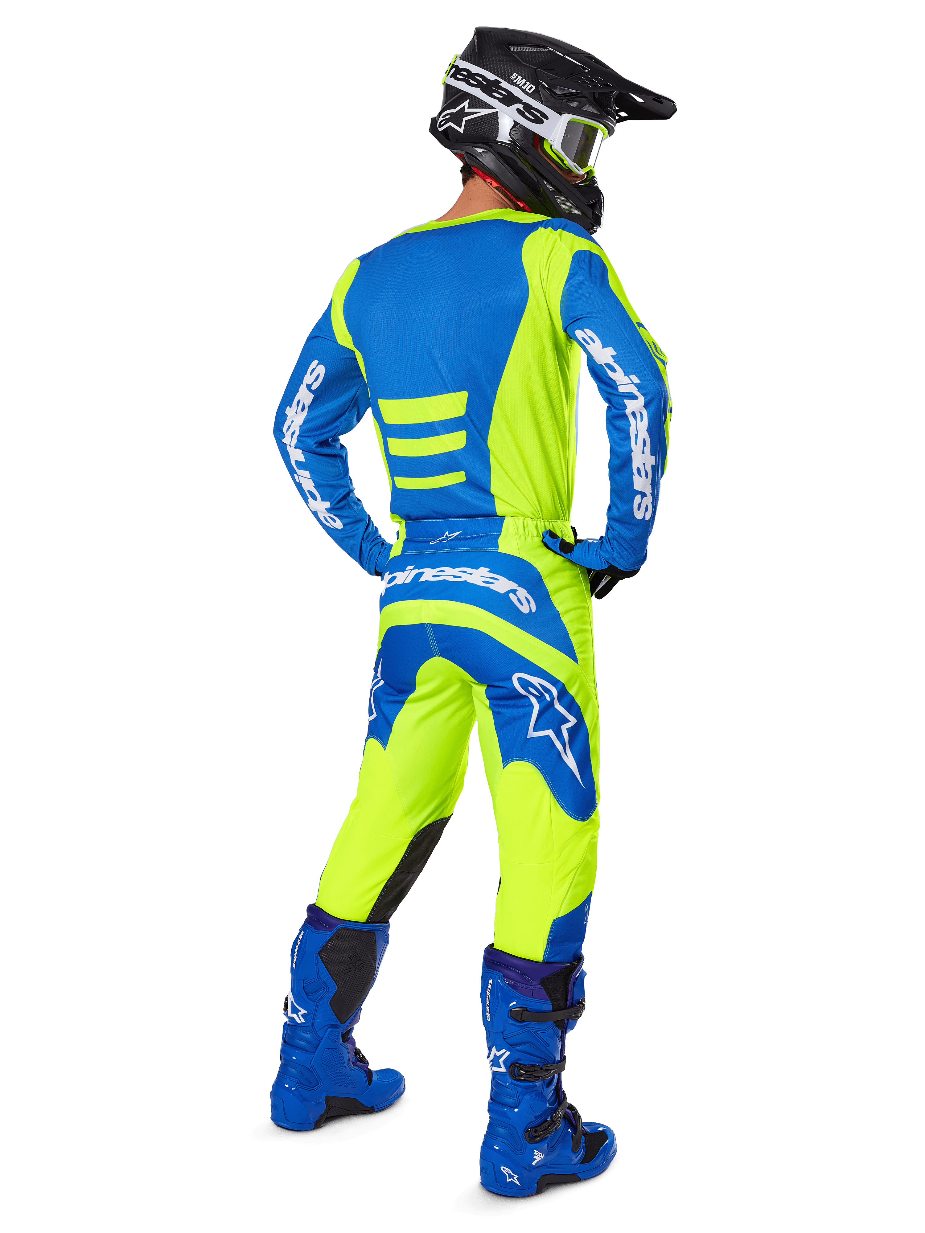 Motocrossrijder van achteren gezien die de Alpinestars 2025 Fluid Haul Gear Set in Yellow Fluo en Blue draagt, met een blauwe jersey met gele accenten, een gele broek met blauwe panelen op het zitvlak en de knieën, gecombineerd met felblauwe laarzen en een zwarte helm.