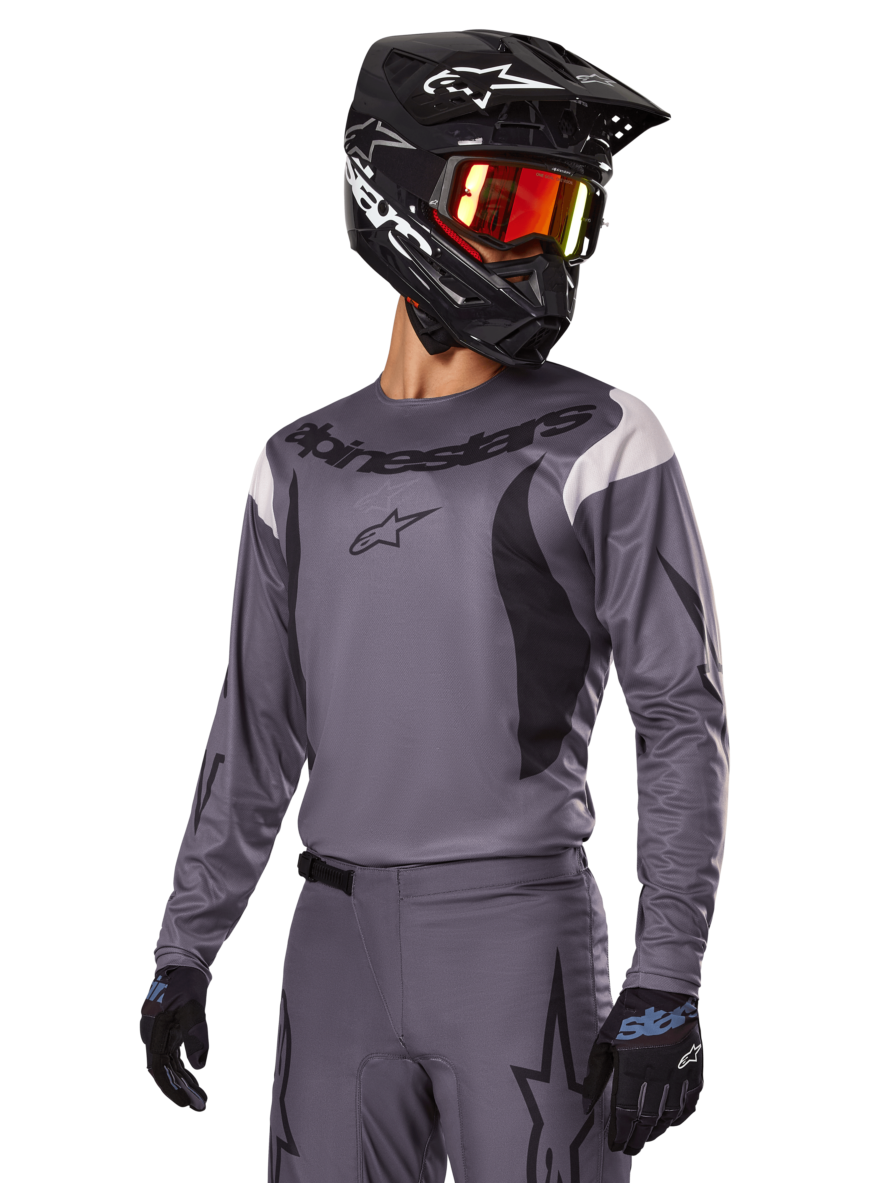 Set d'équipement Alpinestars Fluid Haul 2025, maillot et pantalon de motocross gris avec accents noirs et blancs, porté avec un casque noir, des lunettes rouges et des gants noirs, coupe sportive athlétique pour la conduite tout-terrain