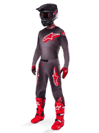 Ensemble d'équipement Alpinestars Supertech Lipan 2025, tenue de motocross complète, maillot gris foncé et rouge avec un grand logo en étoile, pantalon assorti avec des accents rouges et des graphismes d'étoiles, gants rouges et bottes rouge vif avec des boucles blanches, incluant un casque noir mat avec des lunettes rouges.