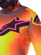 Nahaufnahme des Alpinestars 2025 Supertech Lipan Trikots in Gelb-Rosa, mit einem lebhaften Farbverlauf-Design, einem großen schwarzen Stern-Logo mit rosa Rand auf der Brust und sichtbaren lasergeschnittenen Perforationen für verbesserte Luftzirkulation.