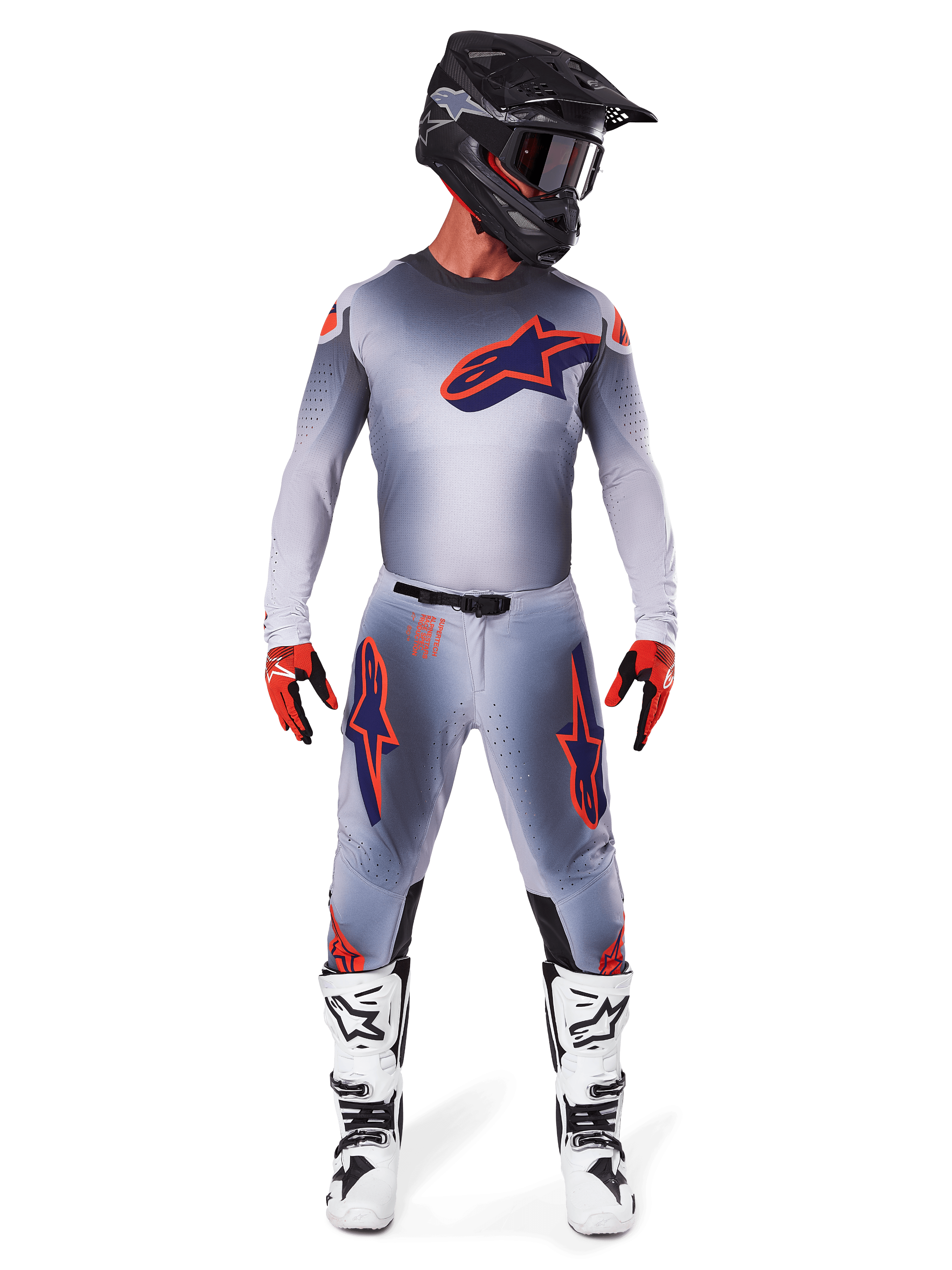 Pilote de motocross portant le maillot Alpinestars Supertech Lipan 2025 en Gris Orange Fluo, présentant un design dégradé gris et un logo orange, associé à un pantalon de motocross assorti, un casque noir, des bottes blanches et des gants orange, équipement de course coordonné de niveau professionnel.