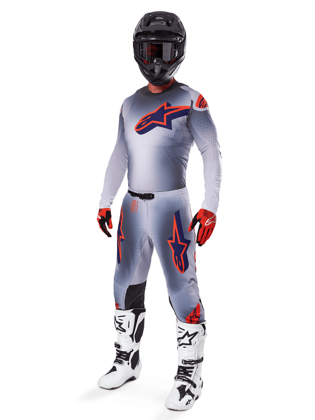 Pilote de motocross portant le maillot Alpinestars 2025 Supertech Lipan en gris et orange fluo, pantalon gris assorti avec des accents orange, casque noir, bottes blanches et noires, et gants orange et noirs, ensemble d'équipement professionnel pour la course tout-terrain