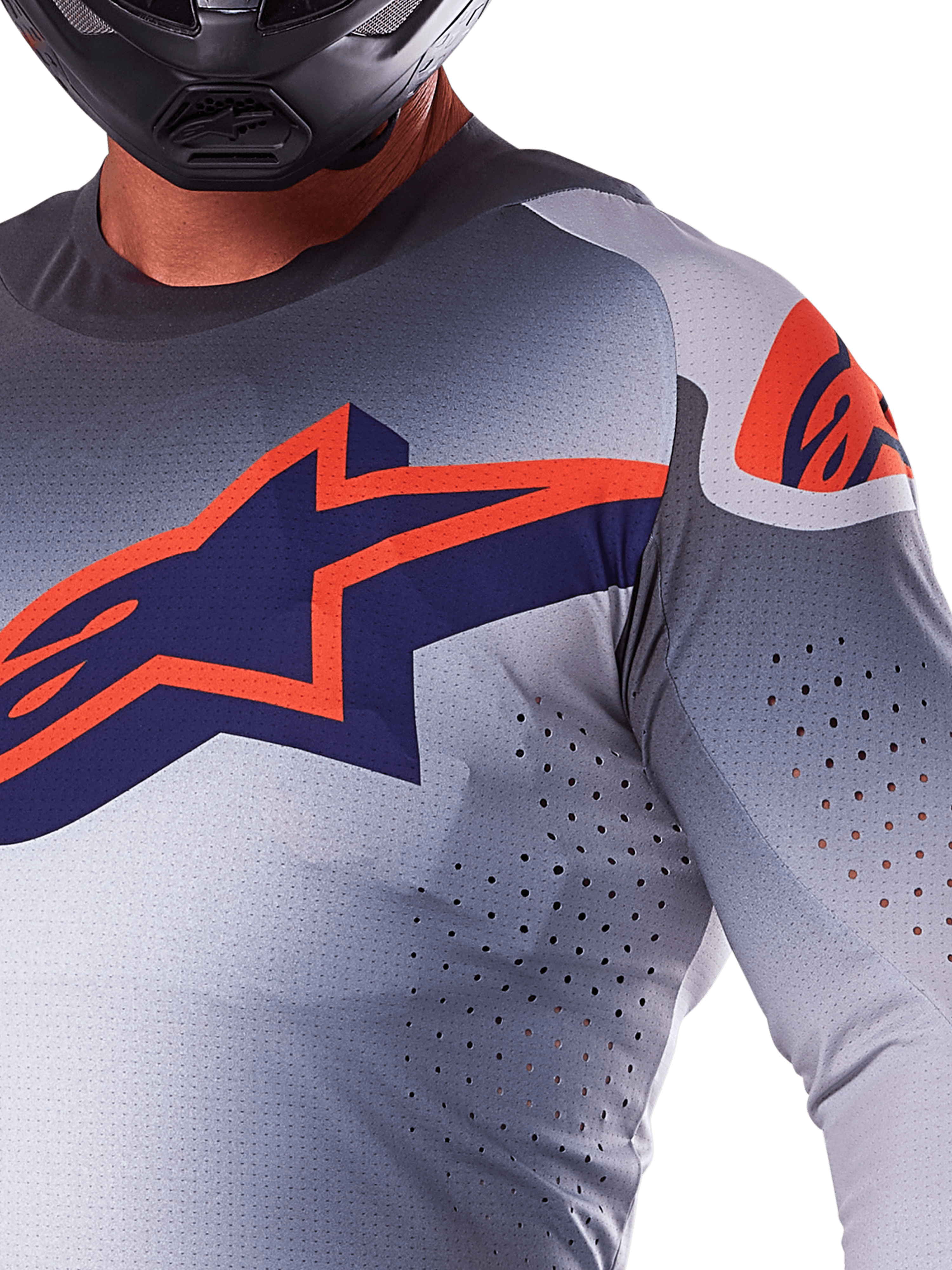 Gros plan d'un pilote portant le maillot Alpinestars 2025 Supertech Lipan, maillot de motocross, gris et orange fluo, avec un grand logo Alpinestars orange sur la poitrine, des perforations de ventilation découpées au laser et un casque noir, équipement de course professionnel.