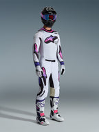 Motocross rider wearing the Alpinestars 2026 Supertech AFD Vista Jersey in White Purple Black, matching motocross pants with pink and purple gradient logos, black helmet with purple goggles, white and black boots, and white gloves, complete professional off-road racing gear set