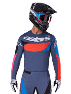 Alpinestars 2025 Techstar Dreem Trikot, Motocross-Jersey, Grau mit blauen, roten und pinkfarbenen Akzenten, mit lasergeschnittenen Perforationen und großem Branding auf der Brust, getragen mit passender Hose und schwarzem Rennhelm
